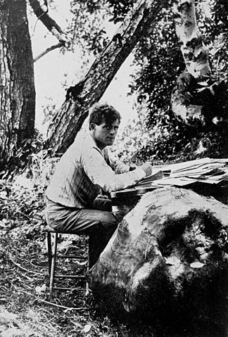 Jack London, writing by a fallen tree, 1905